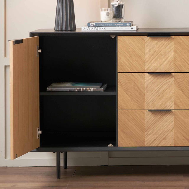Modern cabinet with black interior and wooden exterior, featuring open door and closed drawers.