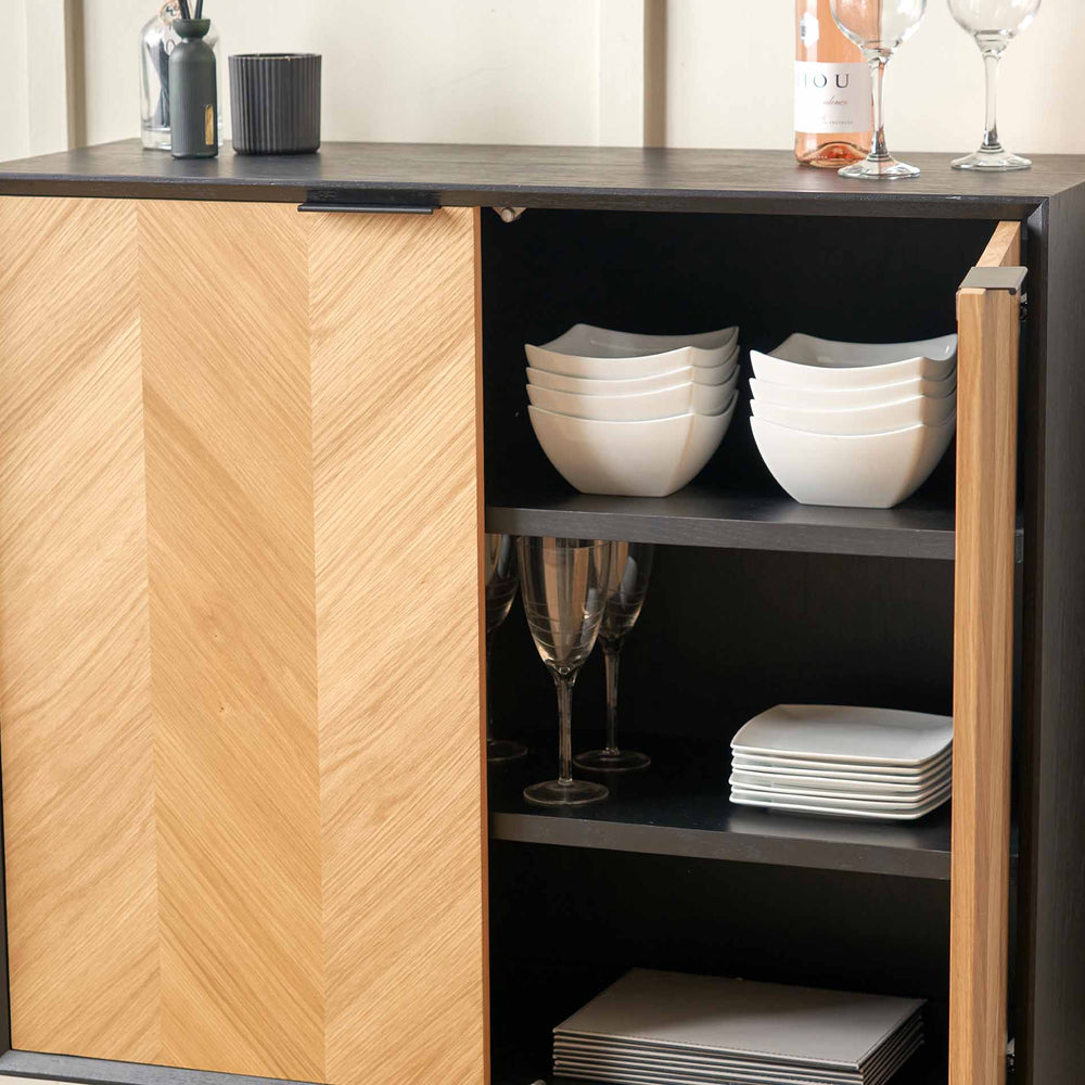 Cabinet with wooden door open, displaying white bowls and plates on shelves.